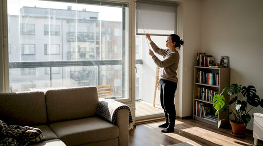 Nainen säätää parvekkeen rullaverhoja asunnossaan.